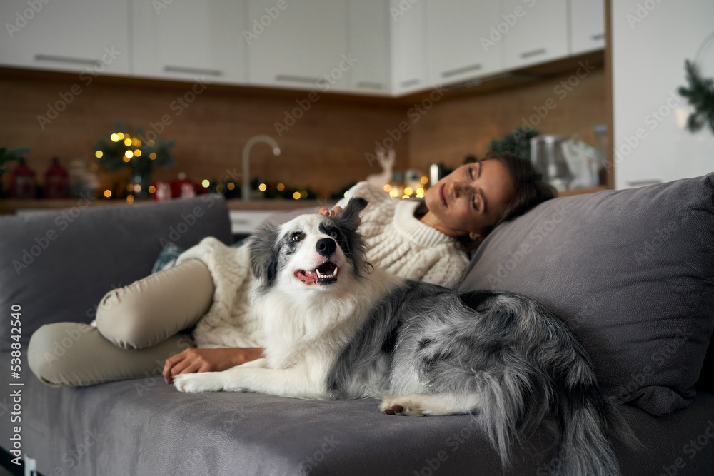 Woman with dog chilling at the sofa during the Christmas