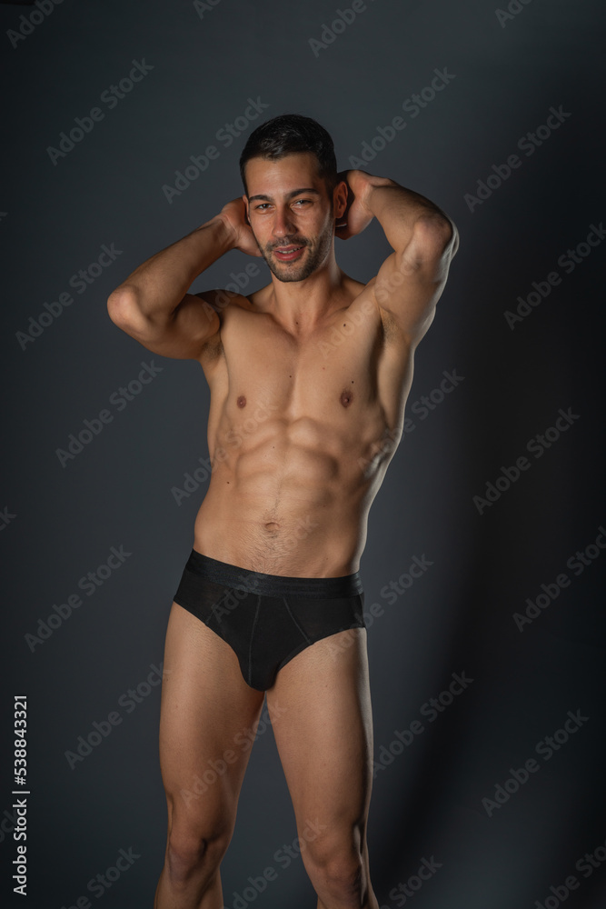 Fashion close-up portrait of a handsome male with bare torso posing in black underwear on isolated background