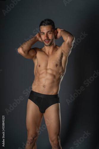 Fashion close-up portrait of a handsome male with bare torso posing in black underwear on isolated background