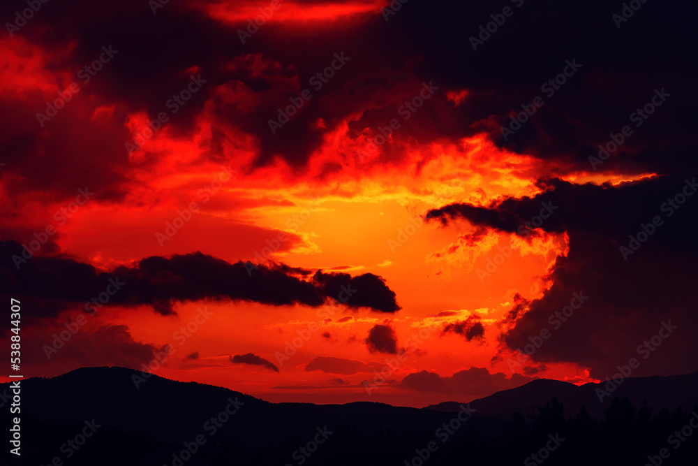 Dark orange sunset sky with heavy stormy clouds in summer