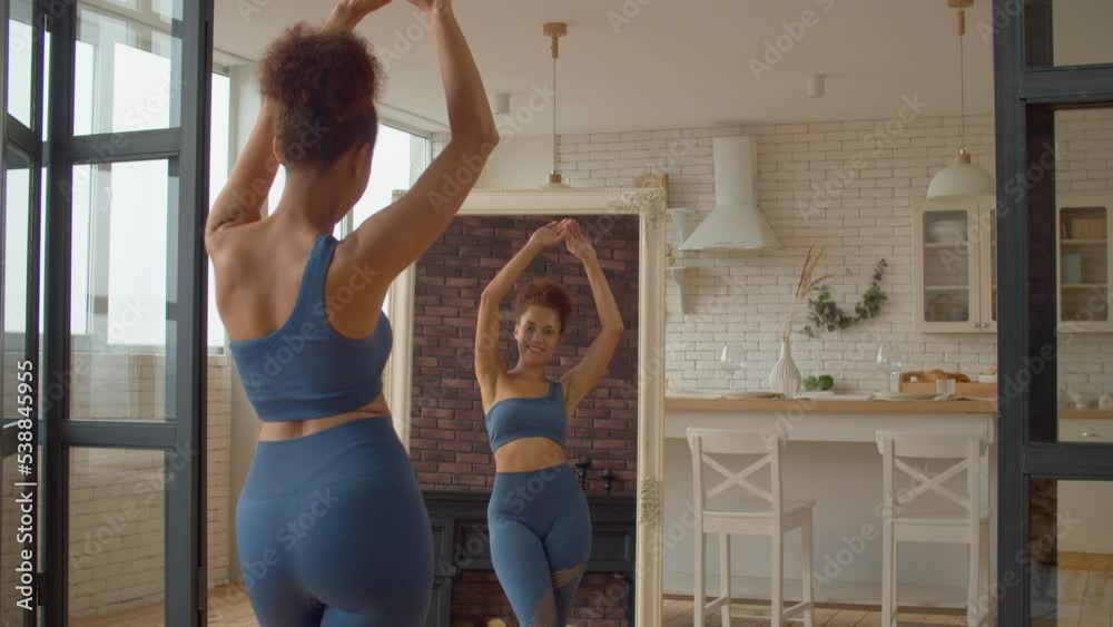 Reflection in mirror of slim smiling attractive African woman in sportswear looking at body shape, rejoicing success of dieting plan and weight loss achievement, expressing cheerful mood and happiness