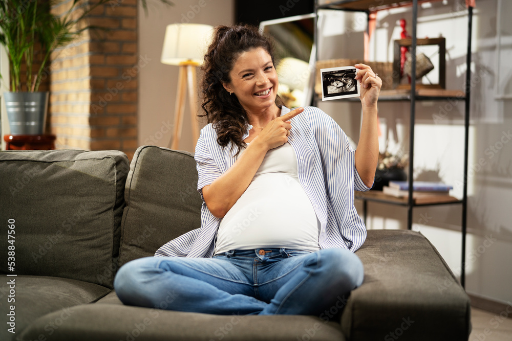 Obraz premium Pregnant woman with ultrasound photo. Beautiful pregnant woman enjoy at home.