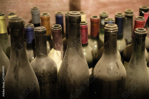 Ancient underground wine cellar with old dusty open wine bottles