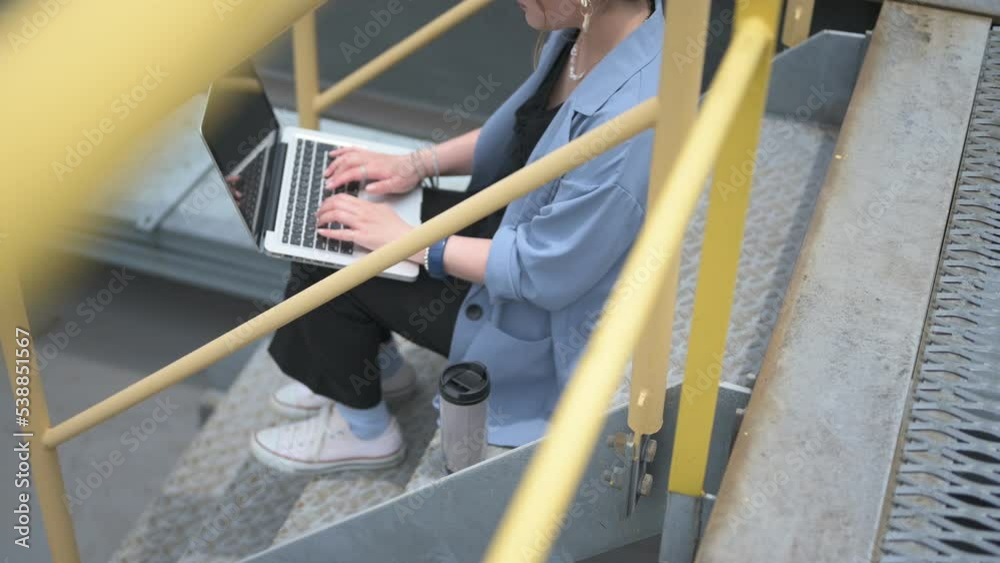 屋上の階段に座ってコンピューターを使用する女性 屋上の階段に座ってコンピューターを使用する女性
