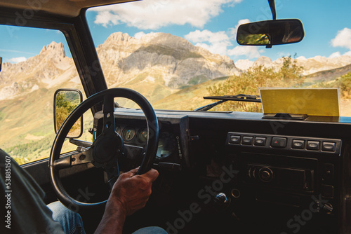hands of unrecognizable people, holding a steering wheel, driving along a mountain road in an all-terrain car. travel and adventure. Active turism.