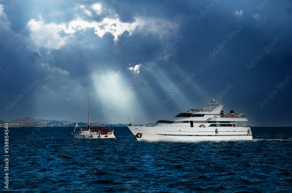 Two yachts on Aegean sea under dramatic sky and sun rays. Greece