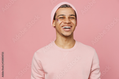 Tableau sur toile Young smiling fun positive cheerful trendy handsome fun gay man wear sweatshirt hat looking camera isolated on plain pastel light pink color background studio portrait Lifestyle lgbtq pride concept