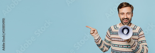 Cuadro en lienzo Young surprised man 30s wear sweater hold scream in megaphone announces discounts sale Hurry up point index finger aside isolated on plain pastel light blue cyan background People lifestyle concept