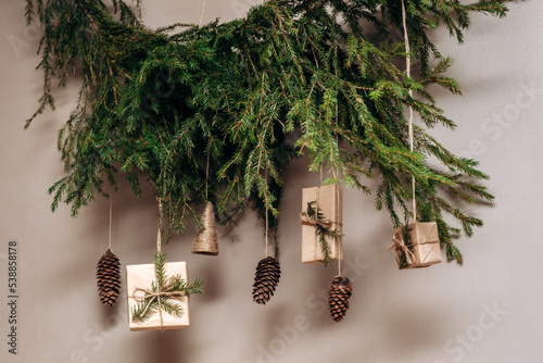 Christmas decor on the wall.Fir branches decorated with gift boxes in craft paper and fir cones.Eco-friendly concept.New Year and Christmas concept.Selective focis,close up. photo