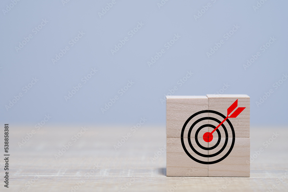 Darts target aim icon on wooden cubes with grey background. Business achievement goal and objective target icon concept. Initiation for planning to reach target. Copy space for text. Darts target aim icon on wooden cubes with grey background. Business achievement goal and objective target icon concept. Initiation for planning to reach target. Copy space for text.