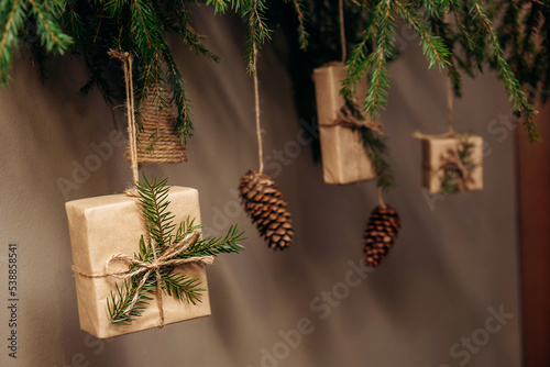 Christmas decor on the wall.Fir branches decorated with gift boxes in craft paper and fir cones.Eco-friendly concept.New Year and Christmas concept.Selective focis,close up. photo