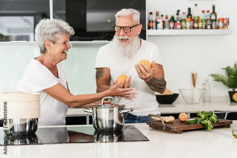 Senior couple cooking at home while preparing vegetarian lunch - Focus on woman hand Senior couple cooking at home while preparing vegetarian lunch - Focus on woman hand