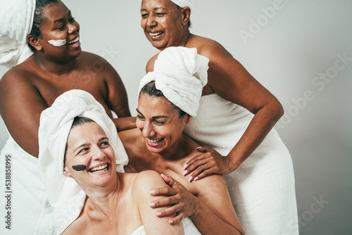 Multigeneration women with diverse skin and body laughing together while wearing body towels - Focus on center woman face