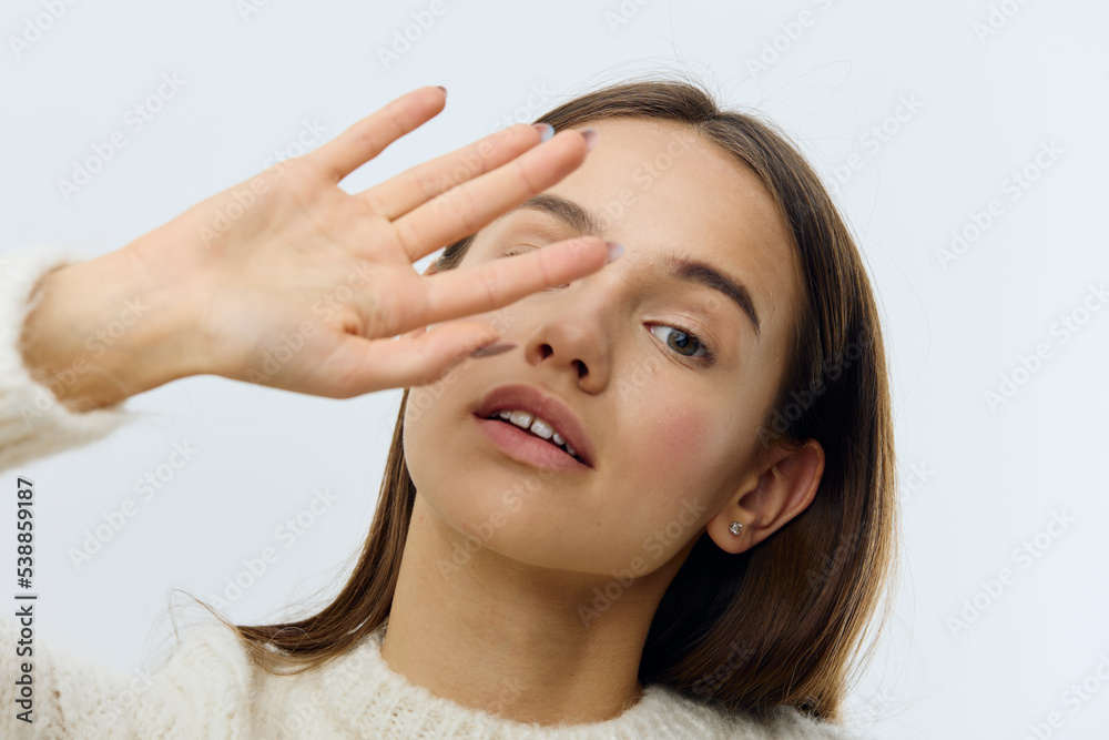 a beautiful, romantic, sophisticated woman stands on a light background, covering her eyes from the camera and thoughtfully looks into the distance with her mouth slightly open. Horizontal Studio a beautiful, romantic, sophisticated woman stands on a light background, covering her eyes from the camera and thoughtfully looks into the distance with her mouth slightly open. Horizontal Studio