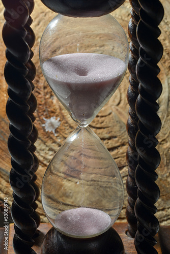 hourglass with running white sand and braided wooden handles