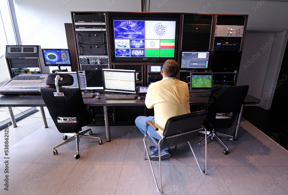 Operator sitting in a control room of a stadium, football match