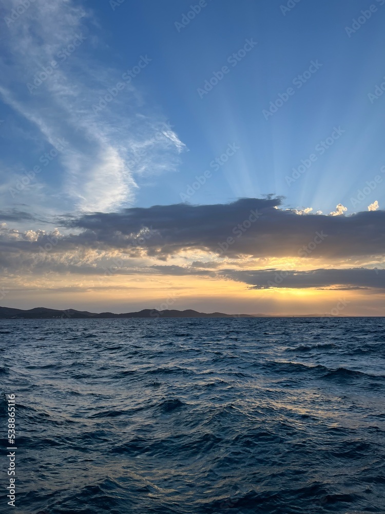 Sunset at the sea, sea horizon, sun rays through the clouds