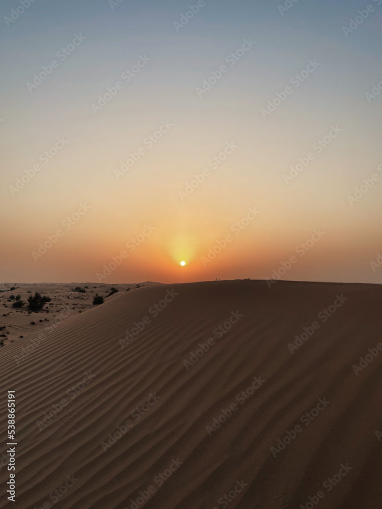 Sunset in the desert. Sun goes down above a dune.