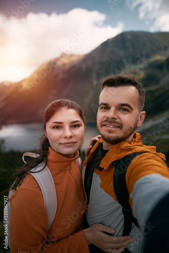 Happy couple hiking. Young couple man and woman in the mountains smiling. © AlexGo