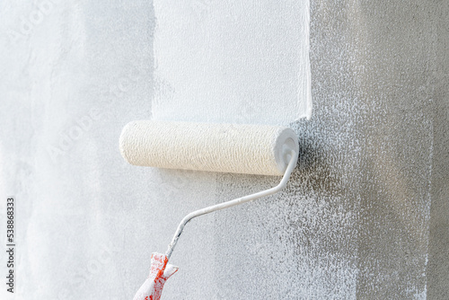 Painting of walls in a white color. Close-up house paint roller, home improvements, horizontal view with copy space.	

