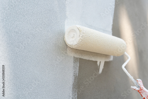 Painting of walls in a white color. Close-up house paint roller, home improvements, horizontal view with copy space.	
