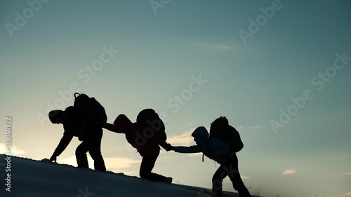 silhouette people climbers going forward mountain sunset. concept climbers with backpacks. teamwork. family trip mountains with backpacks winter sunset. campaign young successful winners. help hand.