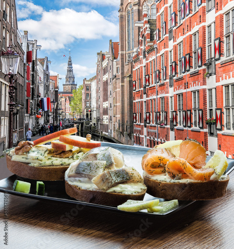 Fotografia Amsterdam city with fish plate (salomon and codfish sandwiches) against canal in