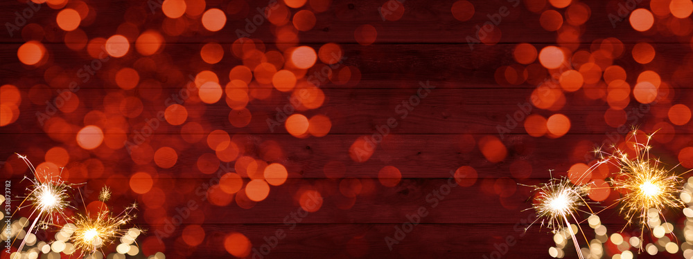 Sylvester, New Year's Eve 2023 Party, New year, Fireworks, Firework celebration background banner panorama long- Sparklers and bokeh lights on rustic red wooden wall texture.