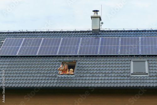 Foto Happy mother and her son waving from skylight window in their new house with solar panels on the roof