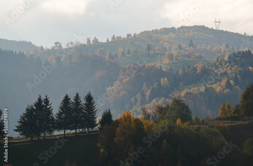 Autumn landscape in Romania. Beautiful sightseeing with the fall landscape from villages of Rucar Bran passage in Transylvania with old houses and folk scenery views. Wide angle view. photo