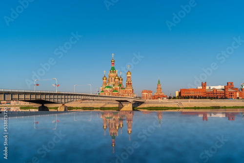 Yoshkar-Ola, Russia. View of Cathedral of the Annunciation of the Blessed Virgin Mary and Blagoveshhenskaya Tower on the embankment of the Kokshaga river wiht reflection. photo