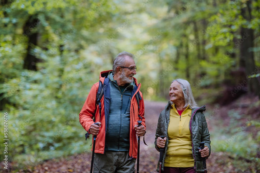 Happy senior couple hiking in autumn forest.