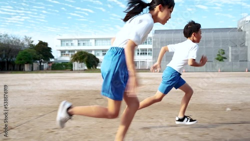 学校の校庭を走っている小学生の男の子と女の子
