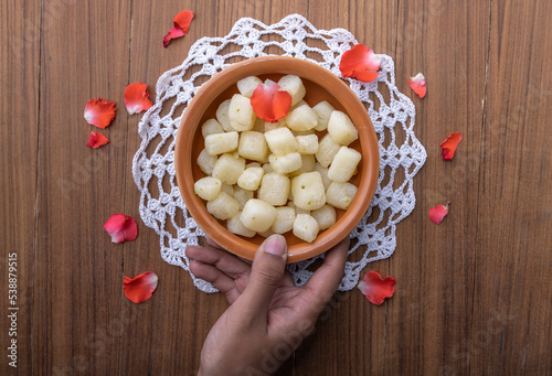 A girl picking up Chena Murk in a bowl, chena murki is a bite-size dry sweet made with paneer dipped in sugar syrup  photo