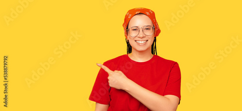 Young happy woman is pointing aside at the yellow copy space beside her. photo