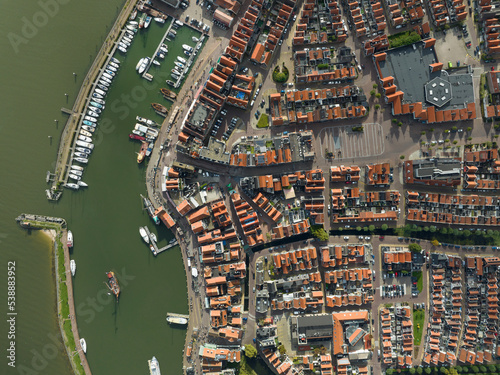 Volendam, Netherlands. Top down overview of traditional dutch fishing village city traditional buildings and harbor. Touristic attraction sky clouds and urban city layout. Aerial drone view.