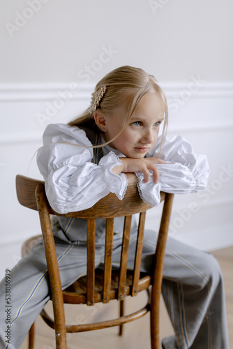 European appearance of the child. Sitting on a chair and posing