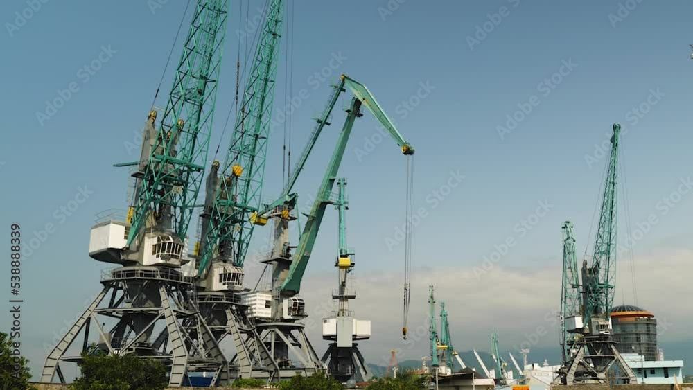 Operation of port cranes. Port sea crane work in a city port. Slow motion. Export and import of dry cargo by sea around the world Operation of port cranes. Port sea crane work in a city port. Slow motion. Export and import of dry cargo by sea around the world