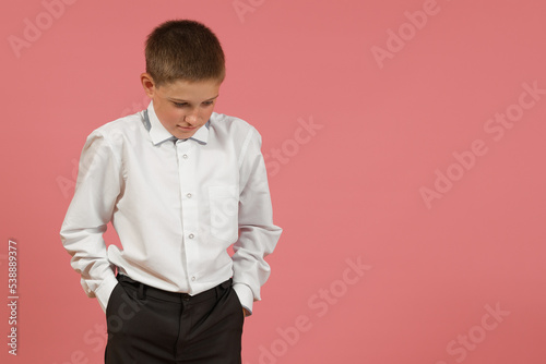 guilty elementary school student in a white shirt put his head down on a colored background