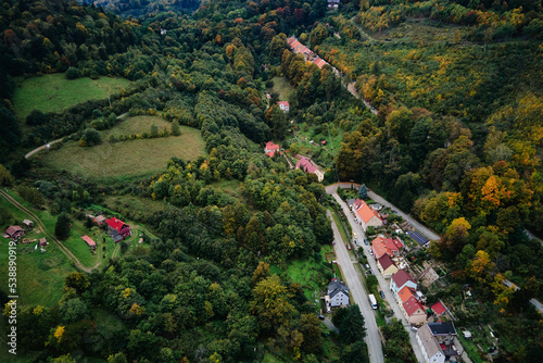 Drone flight over countryside with mountain village and agricultural fields at autumn season. Autumn nature landscape