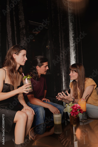 young cheerful people dating and spending time together in club, using a cellphone