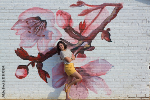 Female model posing in front of wall of Cherry blossoms photo