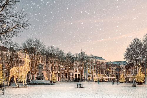 Winter view with snowfall of the central historic square with bars and restaurants in the ancient city center of Deventer, The Netherlands photo