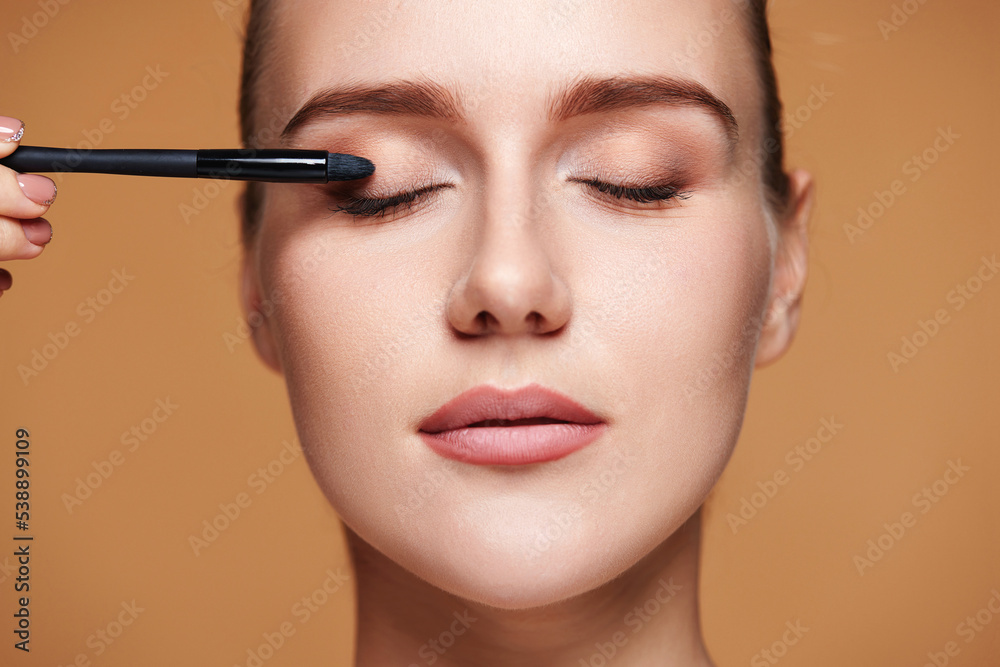 young woman applying eyeshadows on the eyelids