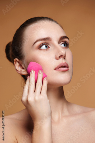 attractive young woman using pink cosmetic sponges