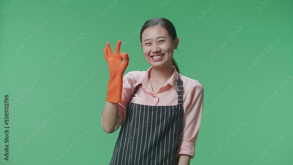 Asian Female Housekeeper With An Apron Showing Ok Gesture And Smiling While Standing In The Green Screen Studio
Asian Female Housekeeper With An Apron Showing Ok Gesture And Smiling While Standing In The Green Screen Studio