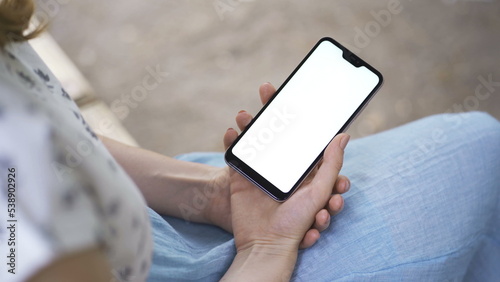 Female hands takes smartphone with white screen. Using Smartphone,Holding Smartphone with Green Screen on a stylish black wooden table © filin174