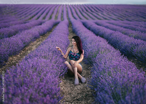 Fototapeta Naklejka Na Ścianę i Meble -  Beautiful girl sits in a lavender field and smiles. The concept of aromatherapy, agricultural production of essential oils.