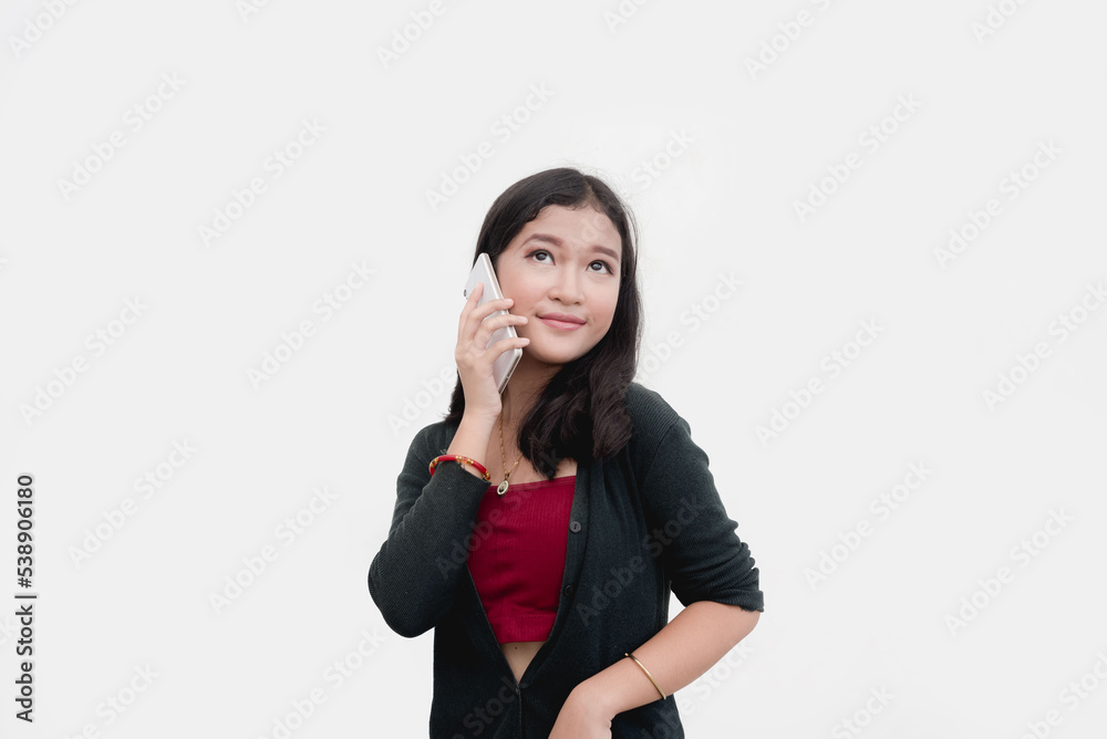 A chatty young lady calls her parents with her cellphone while she poses for a studio shot with a plain white background. A chatty young lady calls her parents with her cellphone while she poses for a studio shot with a plain white background.