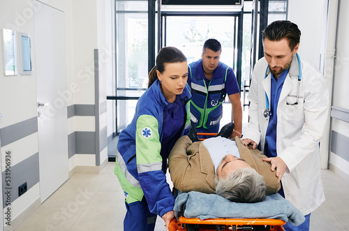 Paramedics and doctor rushing with victim patient on ambulance stretcher on hospital corridor at emergency department. Emergency medical services